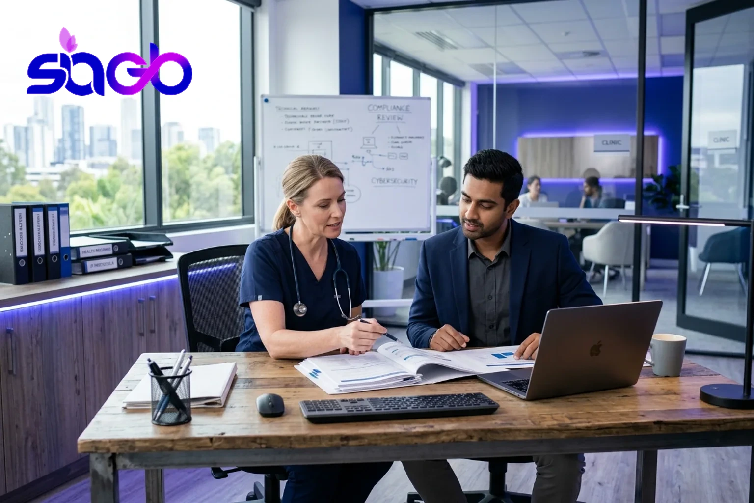 A clinician and IT specialist reviewing compliance documents at a desk.